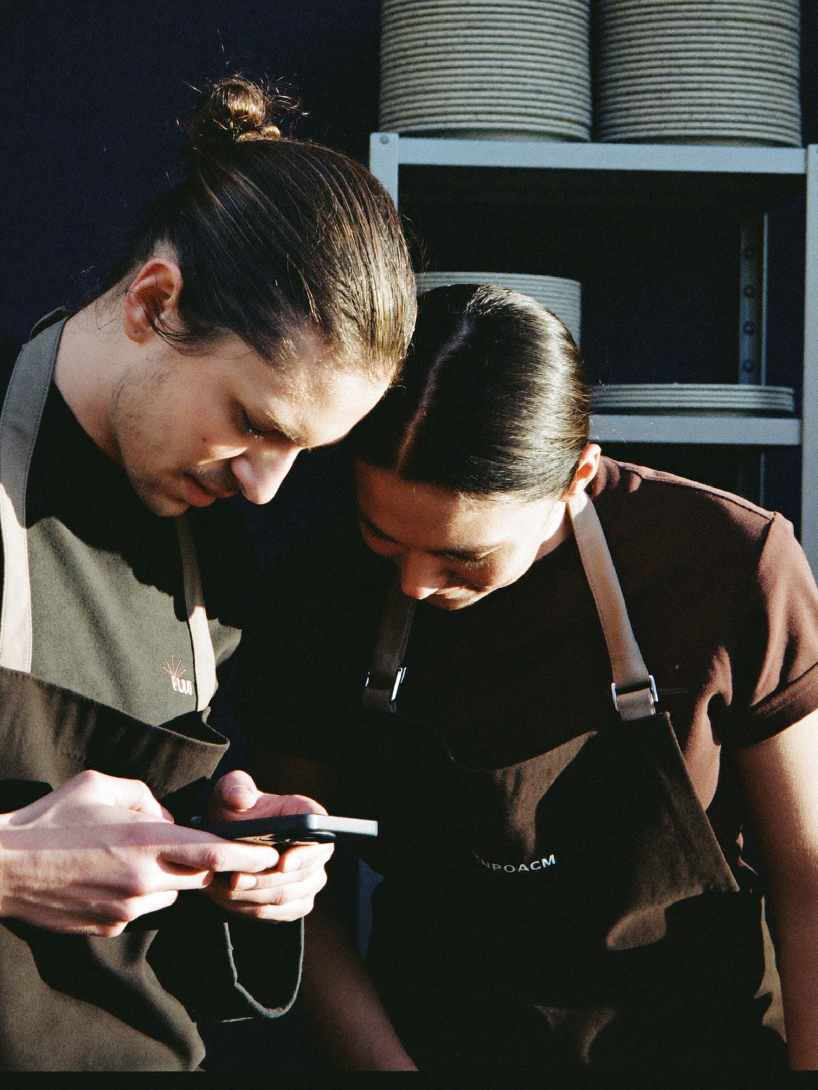 Deux membres du personnel consultent ensemble un planning sur un téléphone.