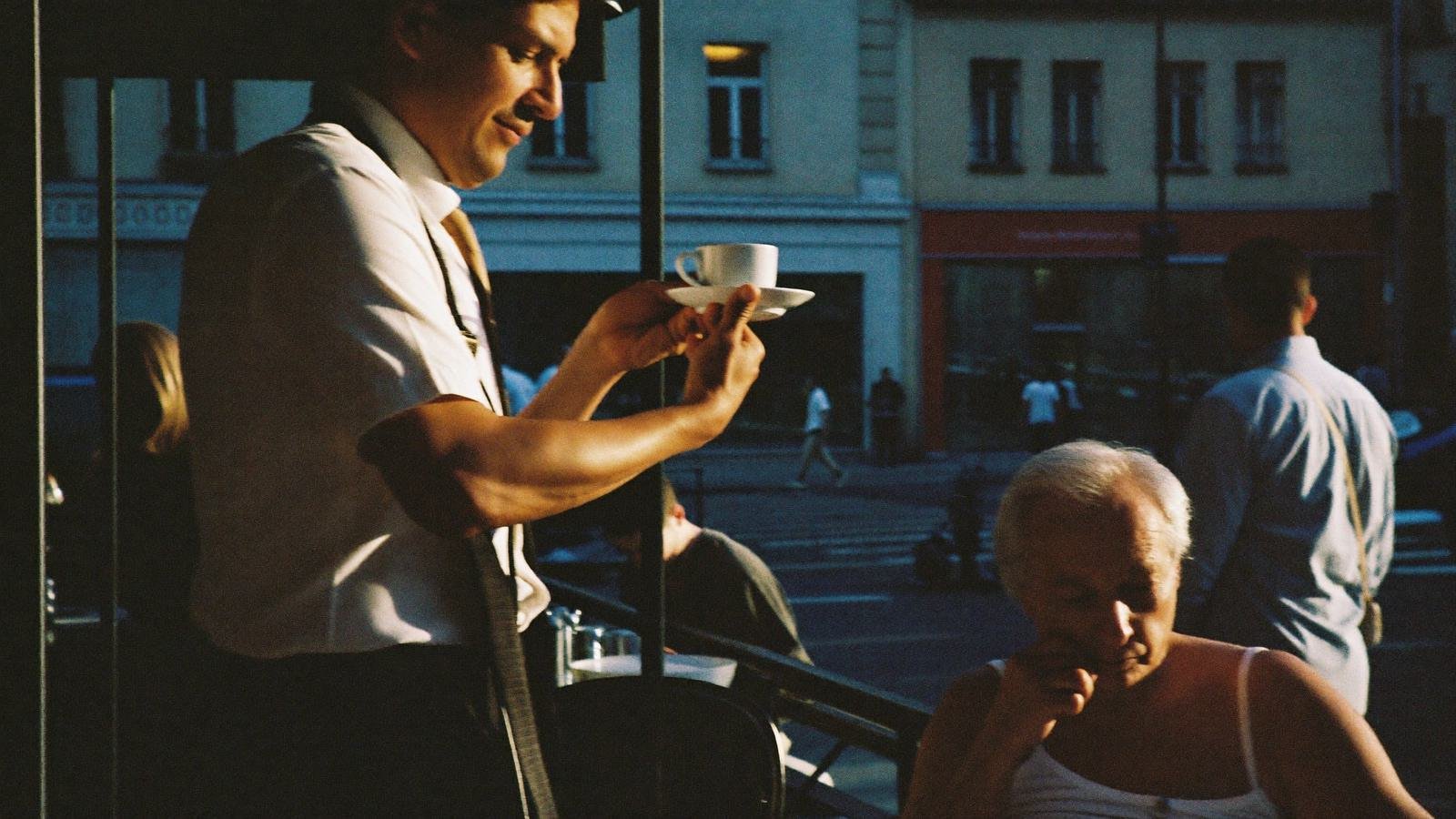 Un serveur prend une commande sur une terrasse bruxelloise en fin d'après-midi.