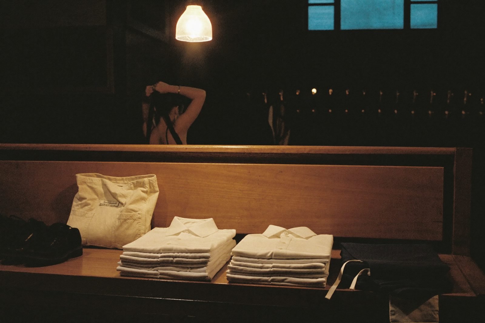 Le vestiaire du personnel avant le service : chemises pliées sur un banc, sac et chaussures.